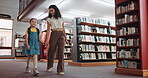 Walking, child and holding hands with woman, library and happy for knowledge development and growth. Pointing, tutor and searching for books with girl, education and smile for scholarship opportunity