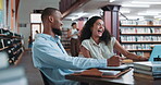 Laughing, man and woman with laptop, library and funny story on break, studying or planning for exam. Happy, students and people with tech for education, learning and humor for joke and friendship