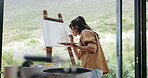 Artist, woman and painting at window with canvas for creative expression, diy project and craft process. Back, mature person and talent for watercolor artwork, nature illustration and design in home.