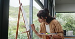 Artist, woman and painting in house with canvas for creative expression, diy project and craft process. Mature, person and drawing at window with talent for oil paint artwork, design or illustration.