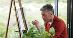 Man, artist and painting on canvas in home for drawing, watercolor and diy sketch for artwork. Mature person, easel and palette for creative picture, art creation and self expression of masterpiece