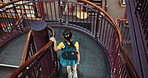 Child, backpack and stairs in library for education, student and walking for learning or knowledge from above. Girl, growth and development for literacy, study or project research at academy campus