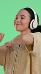 Headphones, dancing and woman in studio listening to music, radio or playlist with energy. Happy, audio tech and female person streaming album or song for party with rhythm by green background.