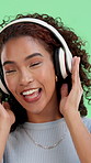 Headphones, singing and woman by green screen with music, radio or album for fun with energy. Happy, audio tech and female person streaming playlist for rhythm with dancing by studio background.
