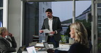Boardroom, team and man with paperwork, talking and presenter with info for financial results on web. Meeting, data analyst and people with laptop for budget review, conversation and risk management