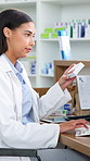 Pharmacist, woman and typing on computer with pills box for research, prescription or drugs info. Healthcare, pharmacy or person in drugstore with tech, medicine instructions and telehealth feedback.
