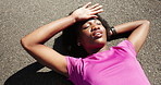 Fitness, tired and black woman relax on ground, summer training and outdoor exercise for wellness. Workout pause, morning run and fatigue athlete lying on road, cardio rest and smile from above