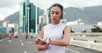 Runner, headphones and woman in city for exercise, cardio workout and training for marathon. Sports, fitness and person listening to music, audio and smart watch for wellness, health or track running