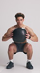 Man, squat and face for training with medicine ball, legs and muscle development on white background. Person, weightlifting and bodybuilder in studio, equipment and shirtless for workout in Colombia