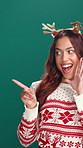 Christmas, promotion and pointing with woman in studio for deal, announcement or sale. Giveaway, space and celebration with happy person on green background for festive season or retail marketing