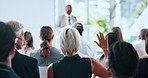 Woman, raised hand and question in audience at conference, insight or feedback for speech at company. Person, gesture and back with discussion, announcement and presentation at corporate convention