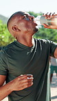 Black man, fitness or drinking water with bottle in nature for hydration, recovery or rest. Active, male person or break with mineral liquid for natural sustainability, thirst or electrolytes in park