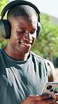 Exercise, headphones and black man with phone in park listening to music, radio and podcast. Happy, rest and person on smartphone for workout, fitness and training with audio outdoor for health