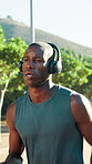 Fitness, man and running with headphones at park for pace training, endurance challenge or playlist. Cardio podcast, black person or jog in nature for exercise, sports performance or wellness workout