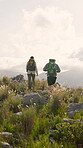 Back, couple and hiking on mountain for adventure date, tourist exploration and bonding together. People, trekking or walking in nature with backpack for connection, wellness or healthy relationship.