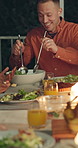 Happy people, night and food with serving at outdoor dinner table for thanksgiving meal or gathering. Salad, dishing and group of friends in late evening with plate, chicken or candle light for feast