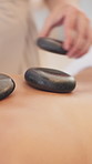 Hands, physical therapy or apply hot stone for wellness, therapeutic massage or spa treatment for back pain. Stress relief, release tension or masseuse help person to relax, warm rocks or luxury care