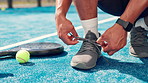 Person, hands and tying shoes on padel court for outdoor match or workout preparation. Closeup, active or athlete getting ready with sneakers, tie or laces for sport game, fitness or challenge