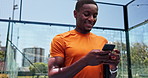 Black man, phone and texting at tennis court, smile and contact on break with web chat at exercise club. Person, athlete and smartphone at training, racket and mobile app for social media in Kenya
