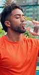 Health, sports and man drinking water on court for tennis break, wellness and nutrition. Hydration, bottle and thirsty athlete with liquid for fitness, electrolytes and padel recovery outdoor