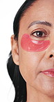Beauty, woman and eye patches in studio for hydration, dark circles and firm skin treatment. Half face, mature person and skincare product for hyaluronic acid or self care routine on white background
