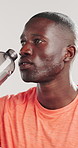 Athlete, black man and drinking water in studio for fitness, hydration and tired from exercise. Person, bottle and rest with refreshing liquid, training fatigue and recovery break on white background
