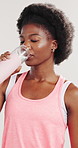 Drinking water, fitness and black woman in studio, wellness and sports challenge on white background. African person, athlete and hydration with healthy drink, liquid and aqua with exercise and tired