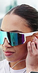 Woman, sunglasses and earphones in city with fitness, smile and listen to music on break for training routine. Person, shades and happy for audio subscription, streaming and exercise in urban town