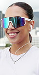 Woman, phone and earphones in city with fitness, sunglasses and listen to music on break for training routine. Person, smartphone and happy with subscription, mobile app or audio for exercise in town