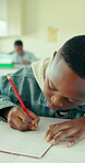 Boy, student and writing in classroom with notebook for math quiz, knowledge or curriculum activity. Child, learner and notes in school with pencil for learning numeracy, study and skill development.