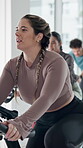 Spin class, active and woman with bike, fitness and training for body strength, wellness or exercise. Gym, endurance and people on machine for workout routine, cardio and cycling for health goals