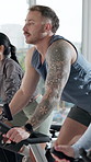 Fitness, man or cycling in spin class with stationary bike for cardio workout, training or wellness. Person, group or energy in gym with equipment for endurance challenge, speed exercise or mobility.