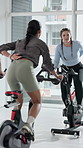 Spin class, personal trainer and women on bike, fitness and training routine for wellness and cardio. Gym, instructor and people on machine for body strength, mobility and cycle for physical health
