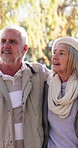 Senior couple, happy and walking with hug in nature for bonding, retirement or love in outdoor park. Mature man, elderly woman and smile in forest for sightseeing adventure or journey together