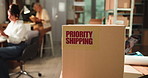 Priority shipping label, box and logistics office for ecommerce, supply chain or distribution. Package, startup or express delivery service with important parcel, sticker or team of business people