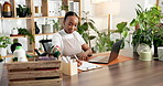 Laptop, online order and writing with black woman florist in plant nursery for small business sales. Computer, gardening product and typing with African entrepreneur in store for startup management