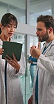 Tablet discussion and doctors in hospital for research on diagnosis, treatment or surgery planning. Digital technology, conversation and healthcare workers with patient information in clinic.