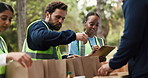Volunteers, packages and people with clipboard, park and organizer with notes for inspection or talk. Outdoor, group and coordinator with checklist for inventory, donations and supply distribution