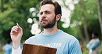 Clipboard, planning and man volunteer outdoor with social responsibility, ngo or charity event. Writing notes, nature and male person with checklist or schedule for community outreach in park.