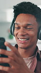 Phone, happy and man with headphones on sofa in home with networking, communication or social media. Audio tech, smile and male person with cellphone for music, texting or chatting in living room.