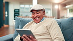 Tablet, happy and senior man on sofa in home reading blog post for news in living room on weekend. Relax, retirement and elderly male person with digital technology for online headline in apartment.