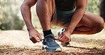 Man, hands and tying with shoes in forest for hiking, fitness preparation or outdoor run in nature. Closeup, male person or runner getting ready with tie, sneaker or laces for trekking or exercise