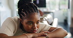 Black woman, sad and thinking on sofa in home, mental health and tired with depression in living room. African person, memory and anxiety on couch, stress and reflection in lounge at apartment