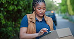 Tablet, courier and typing with black woman outdoor for shipping, distribution service and ecommerce checklist. Online shopping package, delivery address and cargo with person and tech for search