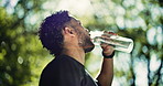 Fitness, man outdoor or drinking water with bottle for sports hydration, workout or exercise break. Bokeh, thirsty person and athlete with beverage in nature for electrolytes, recovery and low angle.