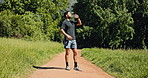Runner, man or drink water in nature with break for sports hydration, check smart watch or wellness. Person outdoor, beverage or tech for exercise recovery, electrolytes or monitor cardio performance