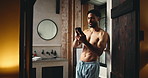 Brushing teeth, entrance and phone with man in bathroom of home for browsing or dental hygiene. App, oral care and social media with shirtless person in apartment for cleaning, health or wellness