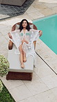 Aerial view, woman and relax on lounger at resort for tanning, luxury vacation and weekend break. Drone, travel and calm person with swimwear at pool for hospitality, serenity and hotel accommodation