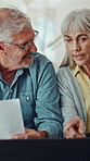 Senior couple, laptop and finance documents on sofa, review or planning for pension at apartment. Elderly man, woman and computer with discussion, paperwork or admin for retirement income in house