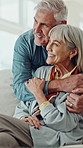 Senior couple, hug and happy on sofa with surprise, bonding and reflection in lounge at house. Elderly man, woman and embrace on couch with point, love or connection with retirement at apartment